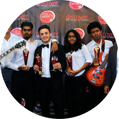 a group of young people standing in front of a backdrop with awards and instruments in their hands
