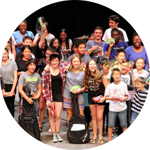 large group of young people standing on stage with musical instruments